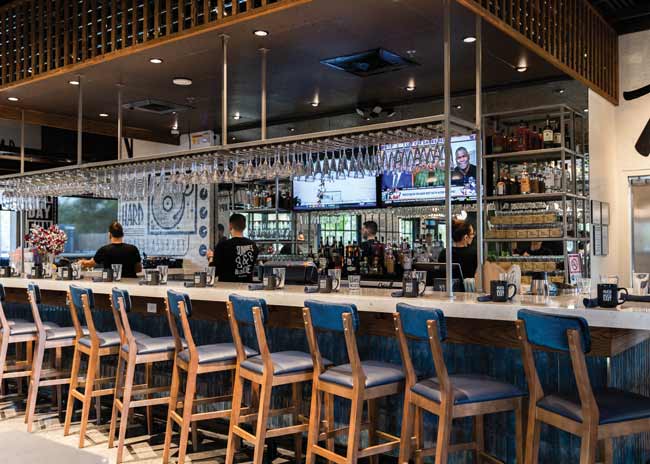 The chain used the space’s existing bar, but added a mirrored bar back along with bar face tiles in navy blue.
