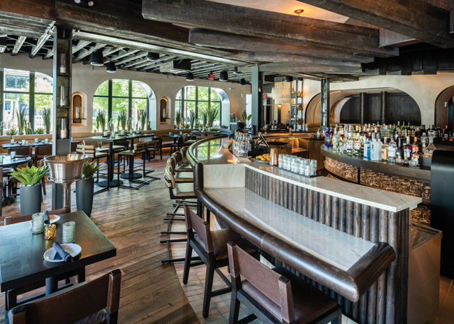 The bar height at bar dLena waterfalls to allow for ADA seating that’s as desirable as any other spot. Image courtesy of GTM Architects