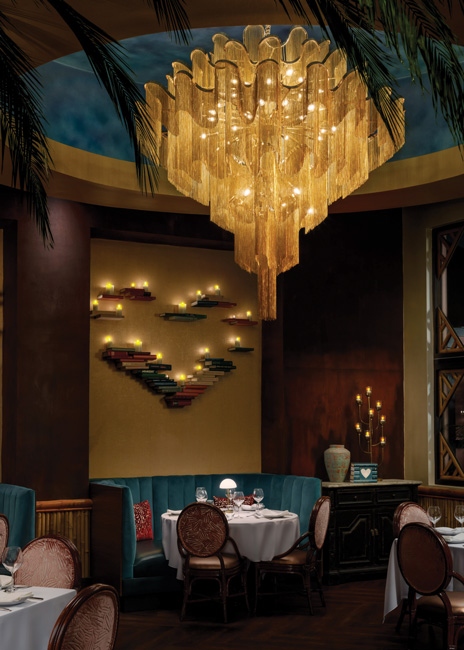 Existing oversized soffits were hung with elaborate, golden mesh chandeliers, while a candle-lit, deconstructed heart wall-art installation carry the La Biblioteca theme upstairs to the dining room. Images courtesy of Dylan Cross